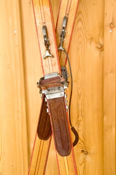 Close up of an antiquated pair of skis leaning against a wooden wall. With space for copy