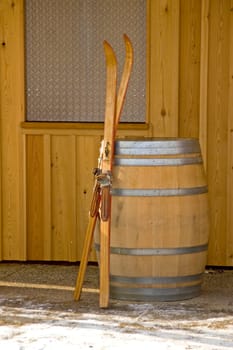 Antiquated pair of skis leaning against a wooden barrel. With space for copy