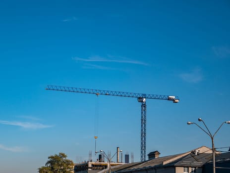 Construction crane on a background of blue sky. Industrial landscape. Place for text.