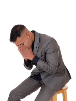 A young man sitting holding his face in his hands thinking about his.problems, looking sad, isolated for white background.
