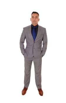 A handsome young man standing with his hands in his pocket in a gray.suit and blue tie, isolated for white background.