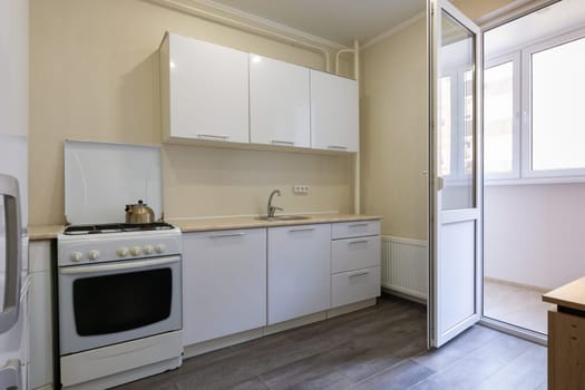 Fragment of the interior of a small kitchen with access to the balcony