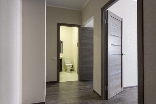 Corridor in a small apartment, open doors to the bathroom and room
