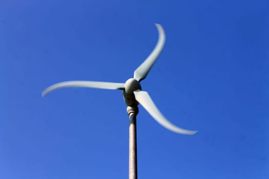 The rotating white windmil in the blue sky