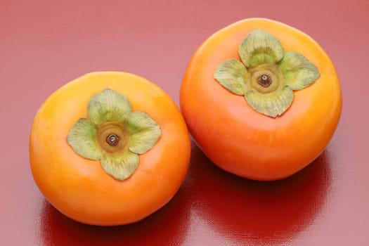 Close up of persimmon fruit on red background