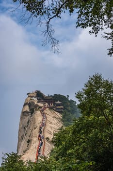 Huashan, China -  August 2019 : Crowds of tourists walking on a narrow ridge on a mountain trail to the West Peak on Huashan mountain, Xian, Shaanxi Province