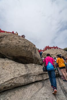 Huashan, China -  August 2019 : Crowds of tourists walking on a mountain trail to the summit of a West Peak on Huashan mountain, Xian, Shaanxi Province