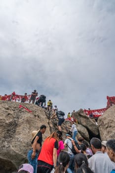 Huashan, China -  August 2019 : Crowds of tourists walking on a mountain trail to the summit of a West Peak on Huashan mountain, Xian, Shaanxi Province