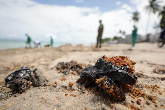 VERA CRUZ, BAHIA / BRAZIL - OCTOBER 18, 2019: People collect oil slick in Praia do Sol, the place was affected by the oil spill in the sea (Joa Souza / Panthermedia).