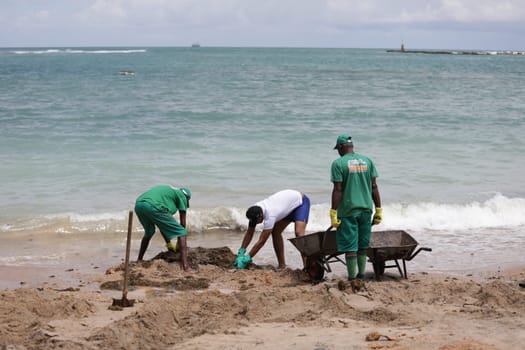 VERA CRUZ, BAHIA / BRAZIL - OCTOBER 18, 2019: People collect oil slick in Praia do Sol, the place was affected by the oil spill in the sea (Joa Souza / Panthermedia).