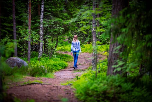 Woman on curved forest road in summer. Trees on sides of road
