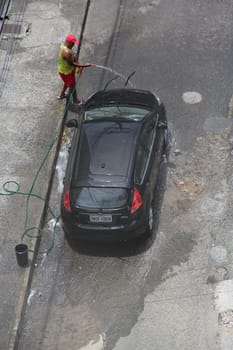 SALVADOR, BAHIA / BRAZIL - December 3, 2014: Man washes car with hose in Cabula neighborhood in Salvador (BA), featuring a waste of drinking water. (Joa Souza / Panthermedia).