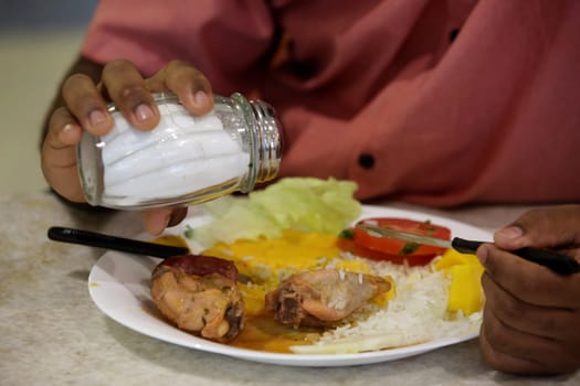 SALVADOR, BAHIA / BRAZIL - July 28, 2017: Person is seen using salt during feature in restaurant in Salvador city (BA).  (Joa Souza / Panthermedia).