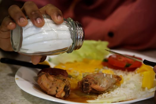SALVADOR, BAHIA / BRAZIL - July 28, 2017: Person is seen using salt during feature in restaurant in Salvador city (BA).  (Joa Souza / Panthermedia).
