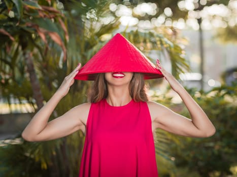 Fashion portrait of a beautiful woman in red conical hat outdoor