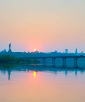 View of Mother Motherland monument above Dnipro river with Paton bridge and Kiev city at sunset, Ukraine