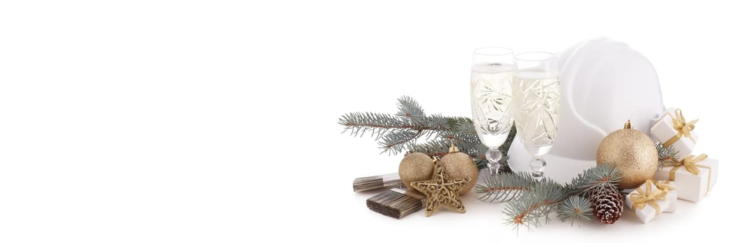 Construction hard hat, fir tree branches, two glasses with champagne, gift boxes and Christmas ornament isolated on a white background. New Year and Christmas construction background