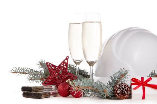 Construction hard hat, fir tree branches, two glasses with champagne, gift boxes and Christmas ornament isolated on a white background. New Year and Christmas construction background
