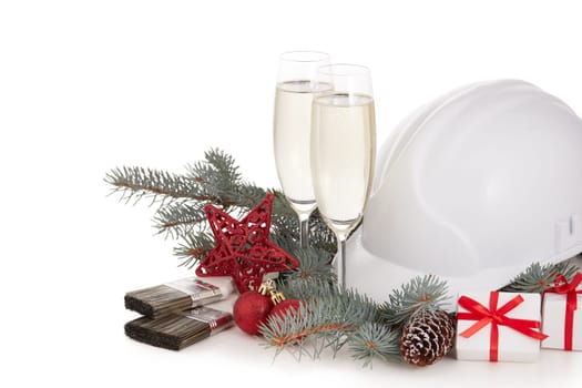 Construction hard hat, fir tree branches, two glasses with champagne, gift boxes and Christmas ornament isolated on a white background. New Year and Christmas construction background