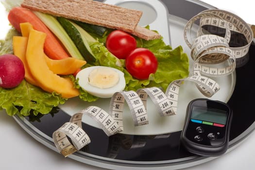 Still life with healthy food, scales, measuring tape and blood glucose meter on white background. Concept: control of level glucose. Healthy lifestyle, healthy food, slimming