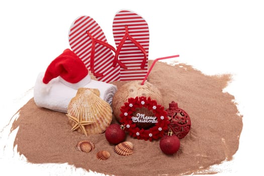 Still life with beach accessories (flip flops, towel, seashells, sand, coconut) and christmas ornaments on white background. Christmas. Winter vacation in warm countries, beach holiday