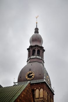 The dome of the clock tower on a background of a gloomy gray sky, Riga, Latvia