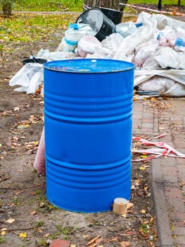 Blue metal barrel on a background of construction debris. Place for text.