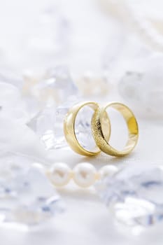 Two golden rings with pearl necklace and on white background as symbol of love and marriage