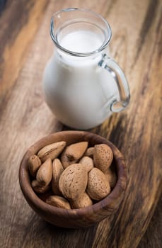 Jar of almond milk with almond nuts on wooden background