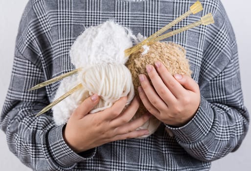 Detail of hands holding white wool for knitting
