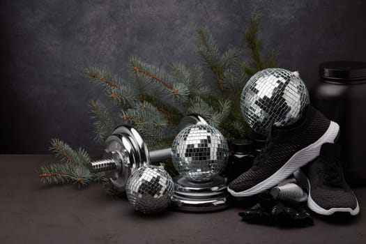 Sports nutrition (supplements), sports equipment, branch of fir, Christmas ornaments on dark grey background with copy space. Fitness, sport or healthy lifestyle concept. New Year and Christmas.