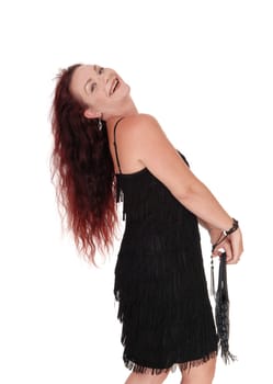 A beautiful woman standing in a black dress in profile with her long.red hair falling in the back, isolated for white background.