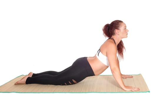 A middle age woman in sports outfit doing push ups on a mad.with her red hair and nice figure, isolated for white background.