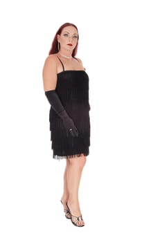 A beautiful woman standing in a black dress in profile with her long.red hair falling in the back and cloves, isolated for white background.