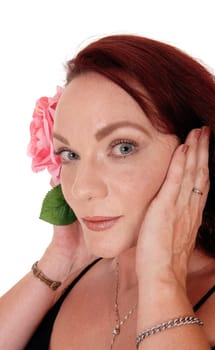 A close up picture of a pretty woman with long red hair holding one.pink rose on her face, looking serious, isolated for white background.