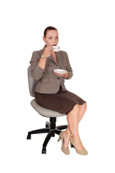 A Gorgeous business woman sitting all dressed up on a chair and.having a cup of coffee, isolated for white background.