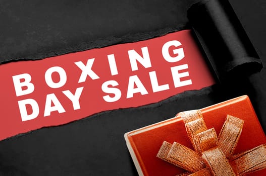 Gift box with a ripped paper showing Boxing Day Sale text on a red background