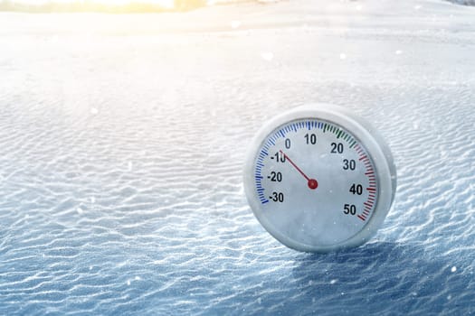 Thermometer with the low temperature at winter with snowfall background