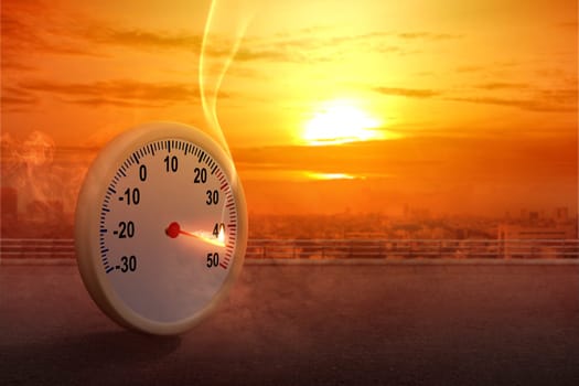 The thermometer on the street with a high temperature on the city with a glowing sun background. Heatwave concept