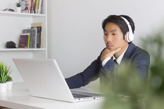 Asian Financial Advisor or Asian Consulting Businessman Seriously Analyze Financial Data in front of Laptop. Asian financial advisor or Asian consulting businessman contact with customer via internet
