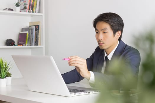 Asian Financial Advisor or Asian Consulting Businessman Seriously Customer Recommend in front of Laptop. Asian financial advisor or Asian consulting businessman contact with customer via internet