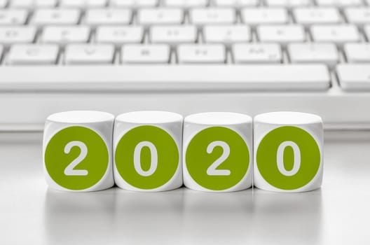 Letter dice in front of a keyboard - 2020