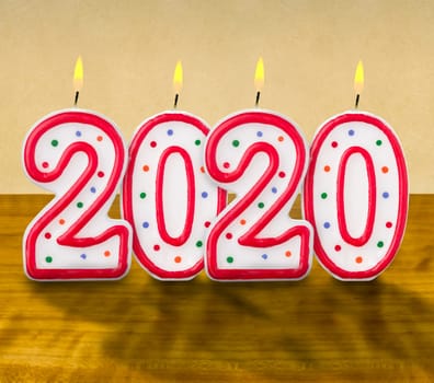 Burning birthday candles on a wooden background - 2020