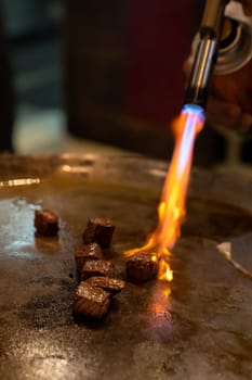 Cooking of beef teppanyaki recipe japanese grilled beef on cooking pan with scraper and gas burner flame