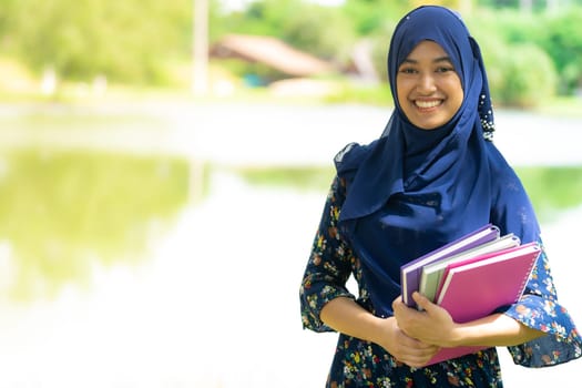 Portrait of good-looking Happy young teenager Muslim islamic asian university girl holding hers books for knowledge and wisdom concept
