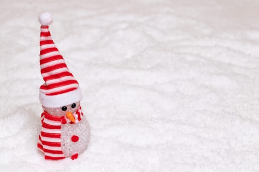 Christmas greeting card template. Christmas background texture with a happy cute winter snowman with red white striped hat and scarf in a snowy winter landscape. Large copy space for your design.