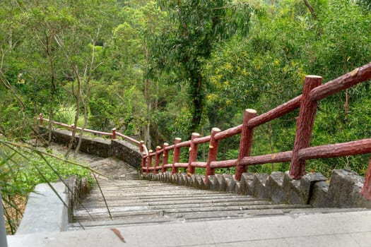Stone staircase on the mountain with a border of red logs on the mountain in Shenzhen, China