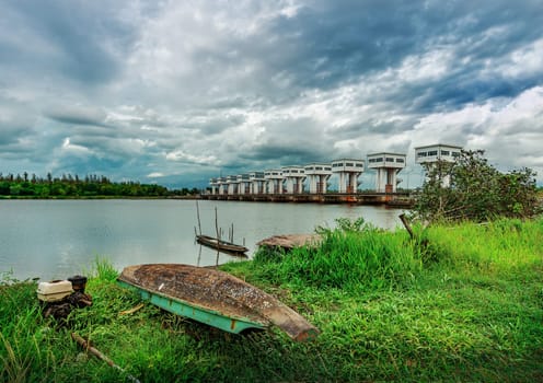 Fishing boat and water barrier and river with color of cloud sky storm in rain season