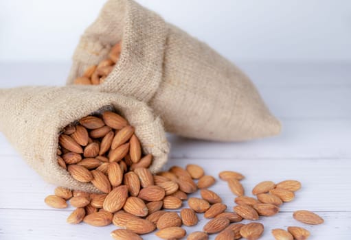 Almond in cloth bag on blurred white wooden table