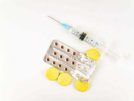 Medical syringe and pills on a white background.